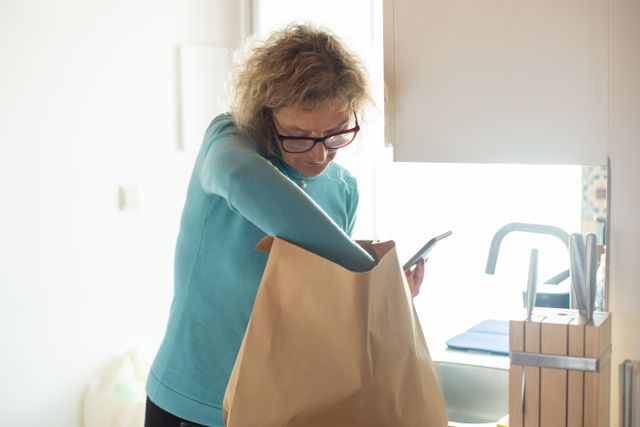 A lady sorting through her groceries in a paper bag