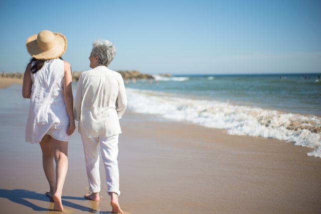 A woman and her elderly parent walking by the beach